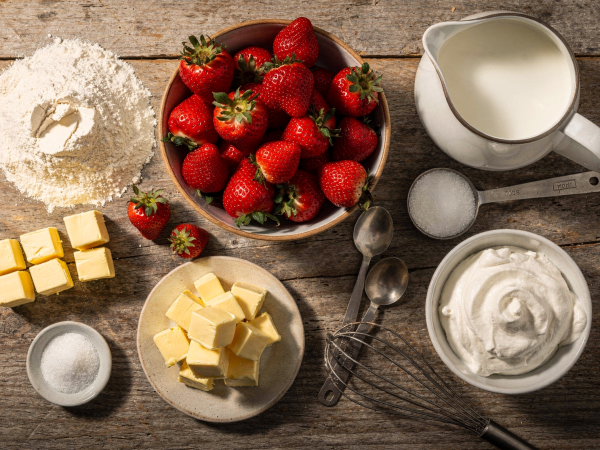 Ingredients laid out for making strawberry shortcake on a wooden kitchen counter